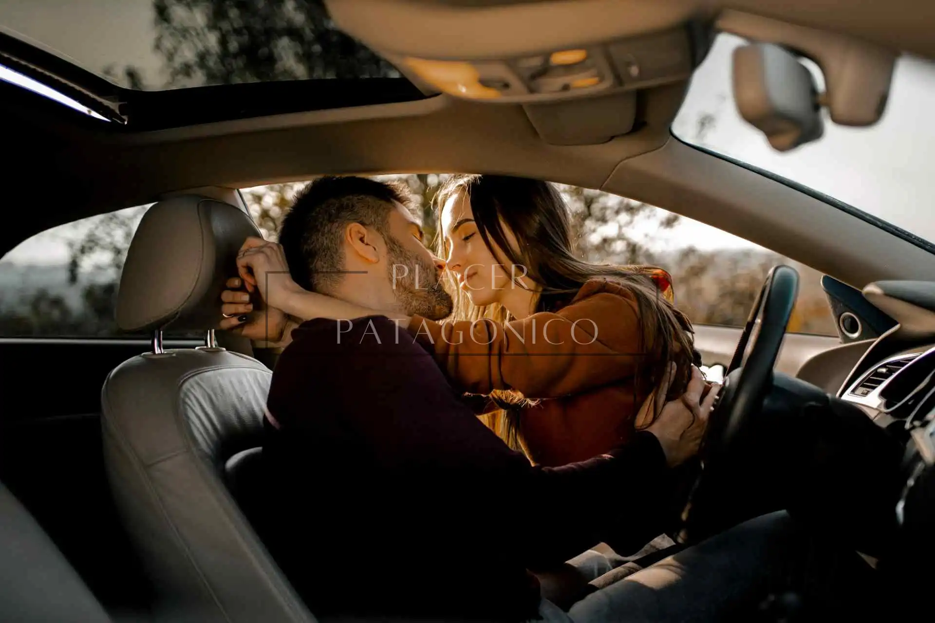 Pareja besándose sensualmente arriba de un vehículo